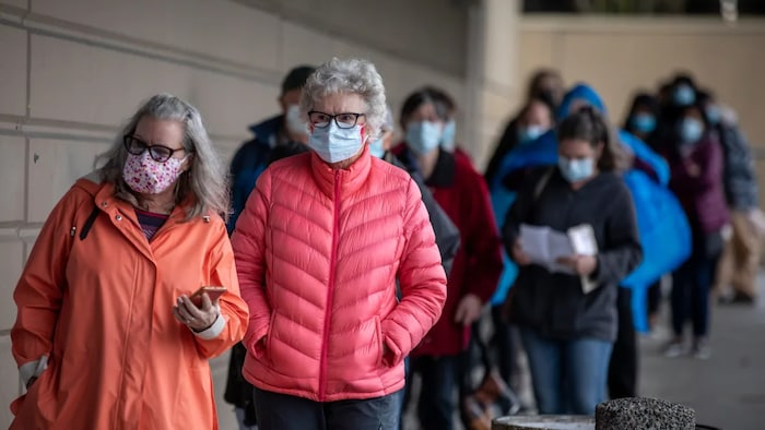 People are pictured lined up to receive their COVID-19 vaccination at a immunization clinic in Surrey, B.C., in March 2021. Canadian immunologists and infectious disease experts believe everyone will need a booster shot at some point, but not yet. 