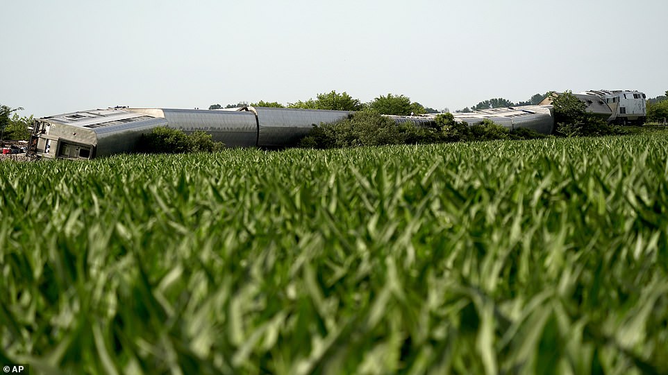 An Amtrak train which derailed after striking a dump truck is seen beyond a corn field Monday, near Mendon, Missouri